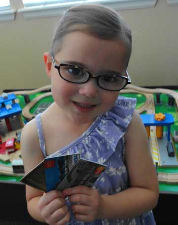 Young girl smiling while holding multiple credit cards.