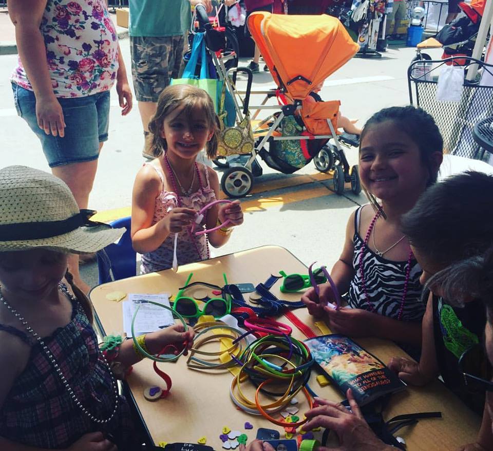 Multiple kids having fun at our craft table at Parker Days fair.