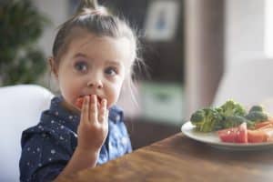 child having healthy eating habits by eating fruits and vegetables