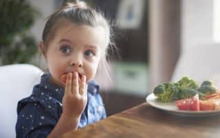 child having healthy eating habits by eating fruits and vegetables