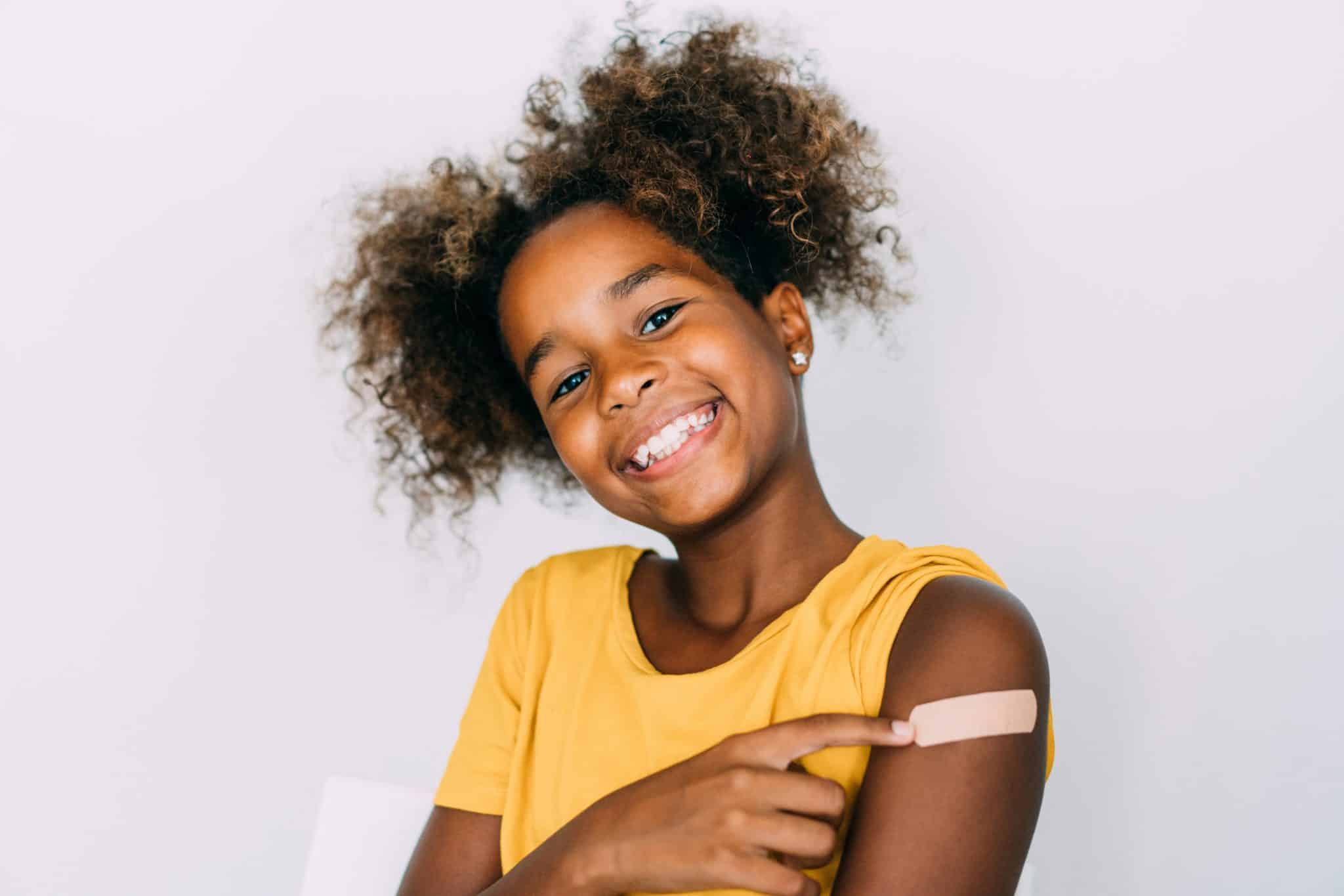 girl smiling after getting a pediatric covid-19 vaccine