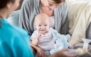 mother holding infant and asking questions to a lactation consultant