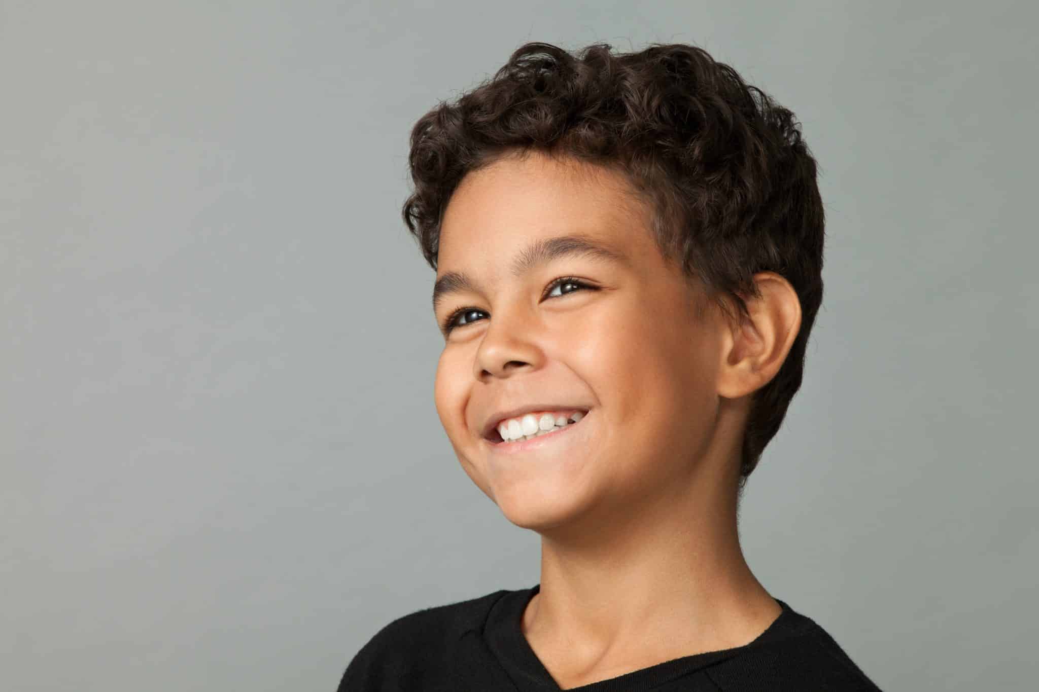 Young boy in black shirt smiling.