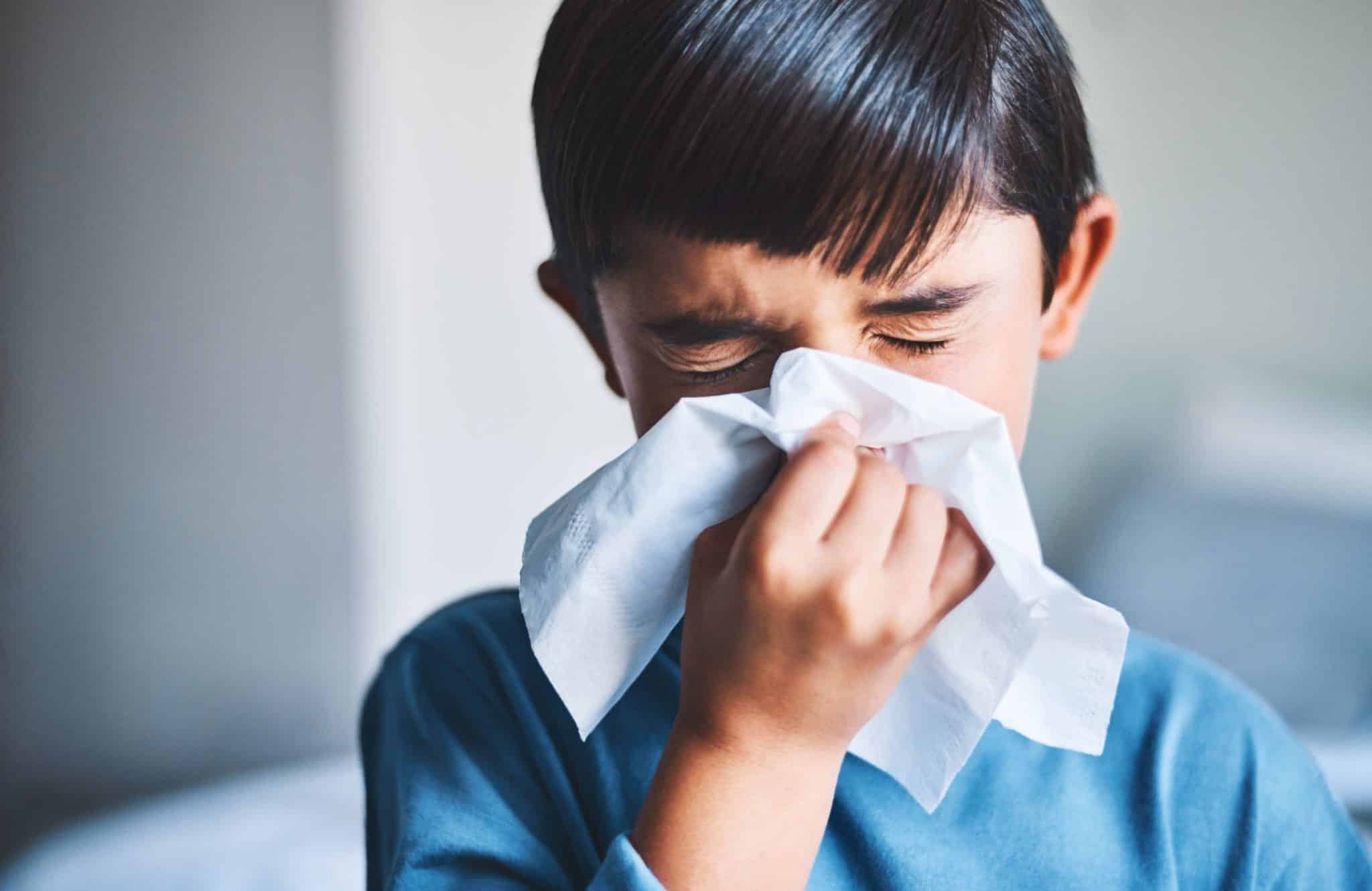 Sick young boy blowing his nose.