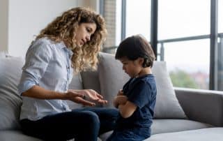 Mother talking to upset child on the couch