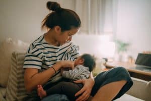 young mother breastfeeding baby in comfortable home