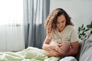 young mother breastfeeding her baby in comfortable home