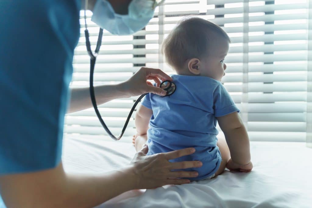 baby sitting on the table at a pediatric sick visit