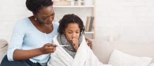 Mother checking her sick daughter's temperature with thermometer.