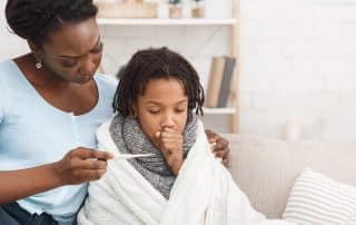 Mother checking her sick daughter's temperature with thermometer.