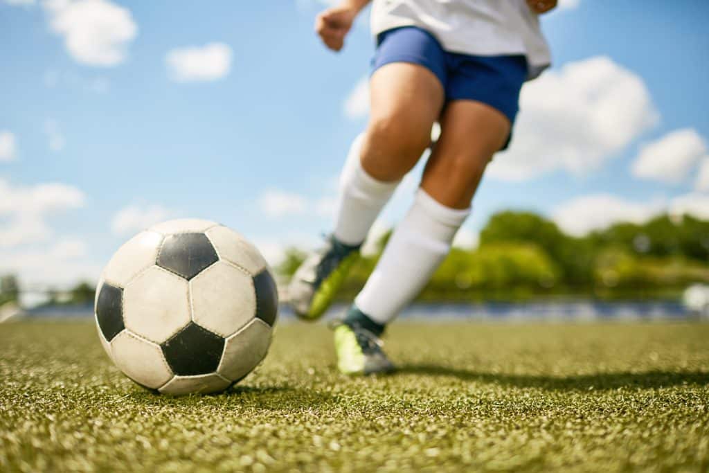 young child kicking a soccer ball after passing a pediatric sports physical in Parker, CO